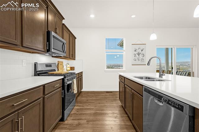 Kitchen with dark wood cabinets, a white island, stainless steel appliances, and wood-look floors.