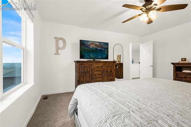 Bedroom with striped bedding, an ornate wood dresser, and a large window overlooking water.