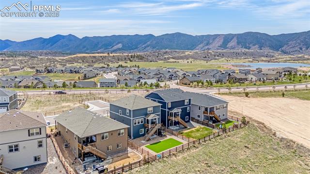 Aerial view of homes in Monument with fenced yards and mountains beyond.