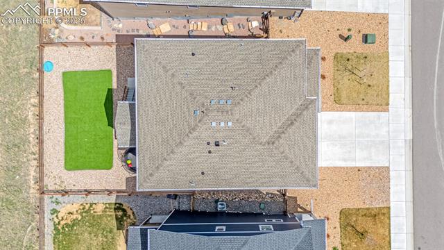 Aerial view of a home with a broad gray shingle roof, artificial turf, and paved walkways.