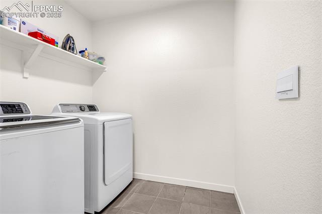 Laundry room with a washer and dryer beneath a shelf of laundry supplies.