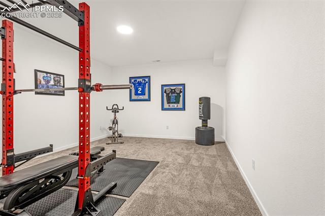 Home gym with a red weight rack, exercise bike, punching bag, and framed jerseys.