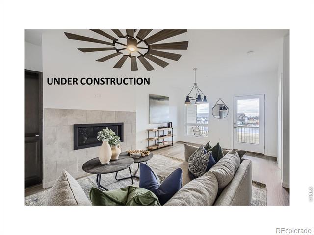 Living room with a tiled fireplace, large radial ceiling fan, and glass door to a balcony.