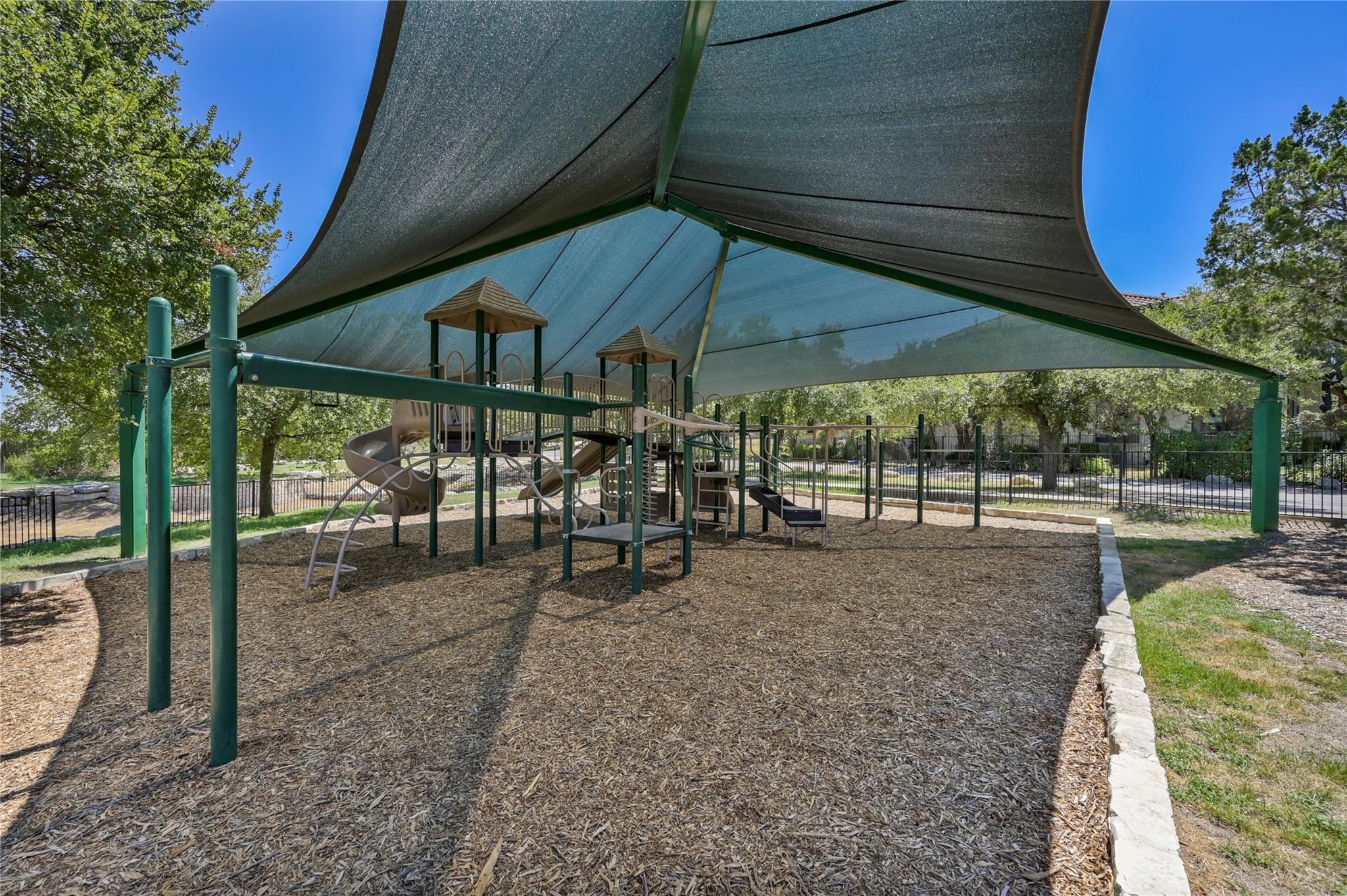 Playground with slides and climbing equipment beneath large shade sails.