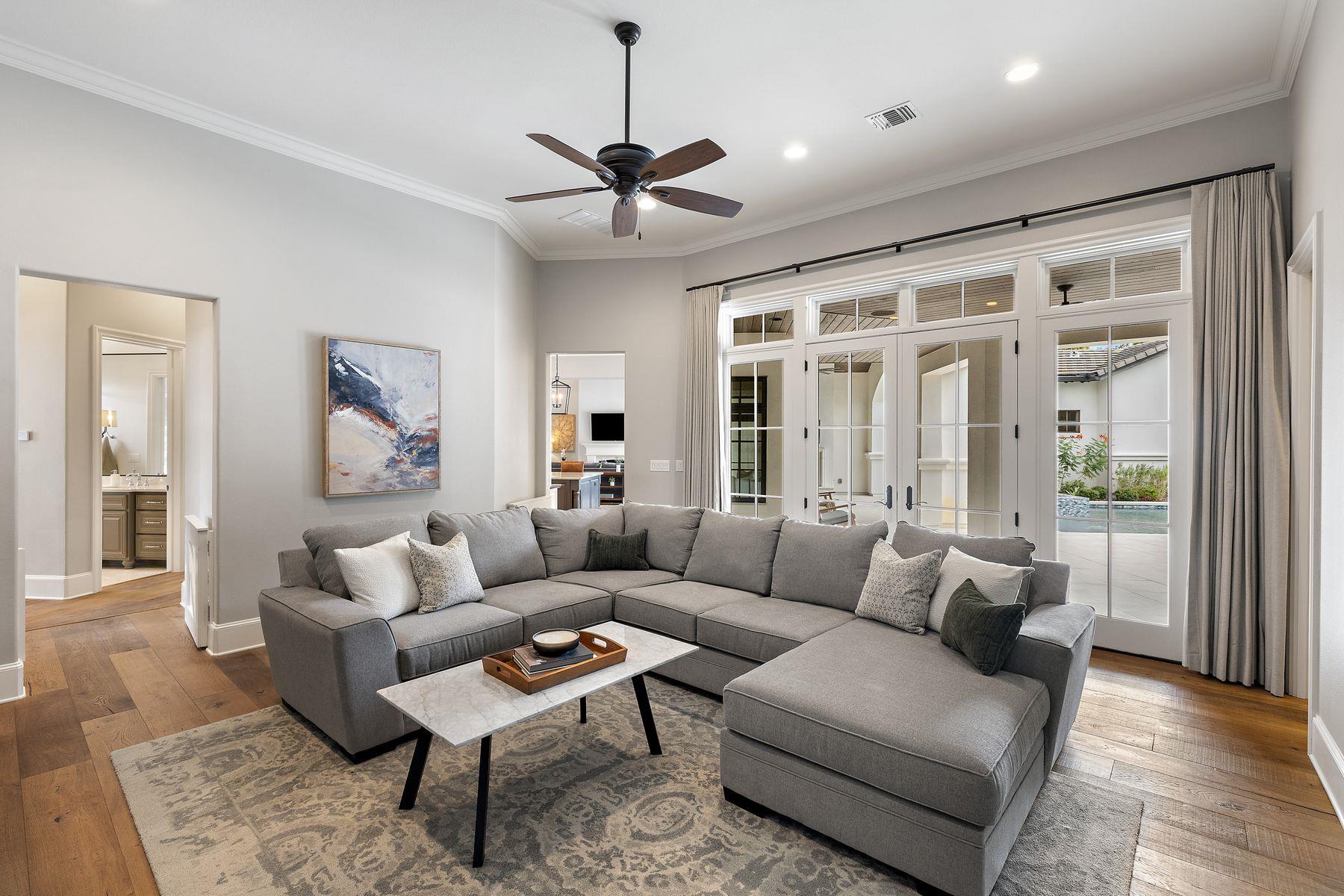 Living room with a gray sectional and French doors overlooking the patio and pool.