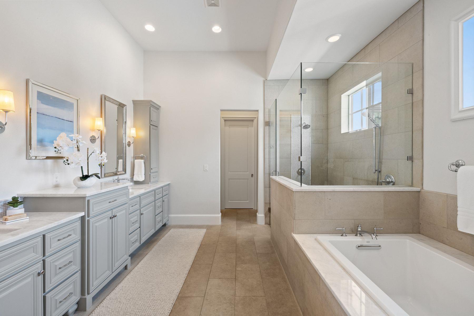 Primary bathroom with double vanity, glass-enclosed tiled shower, and soaking tub.