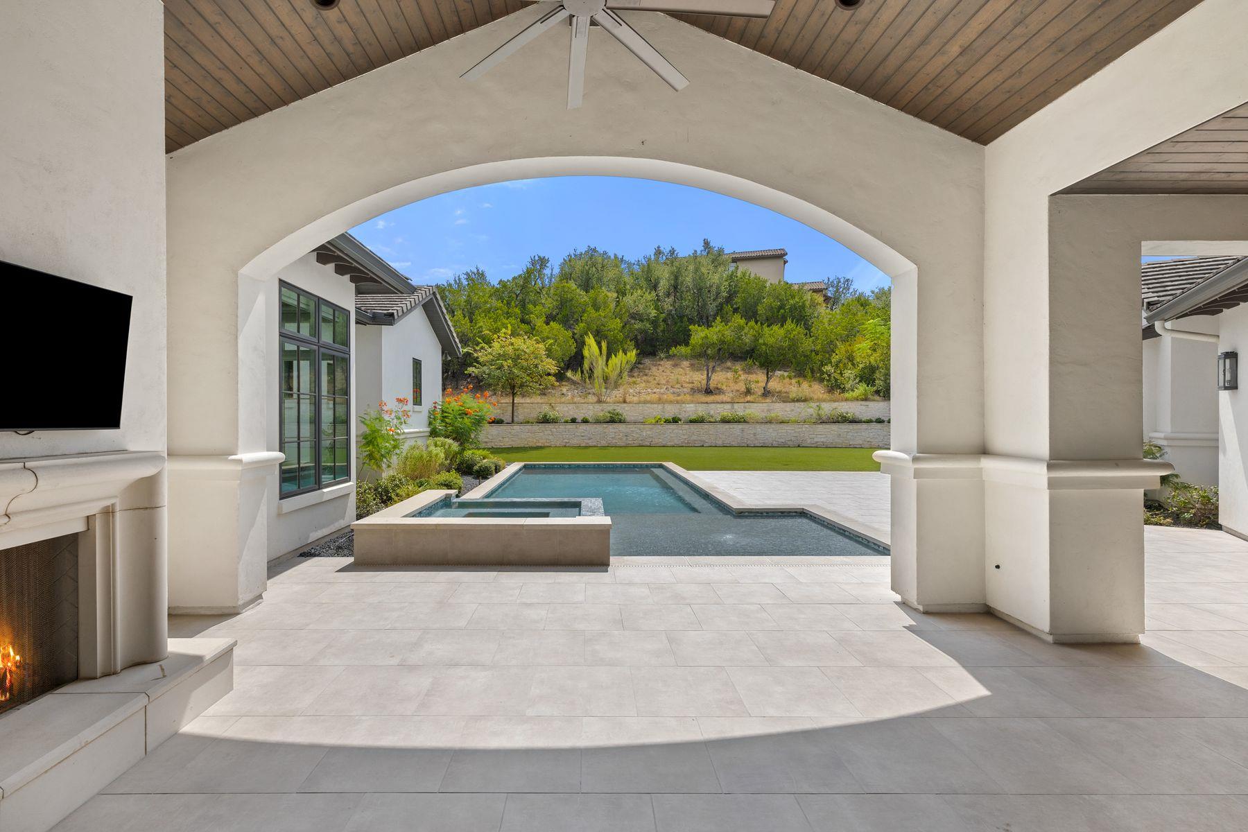 Covered patio with wood ceiling and arched view of a swimming pool and spa.