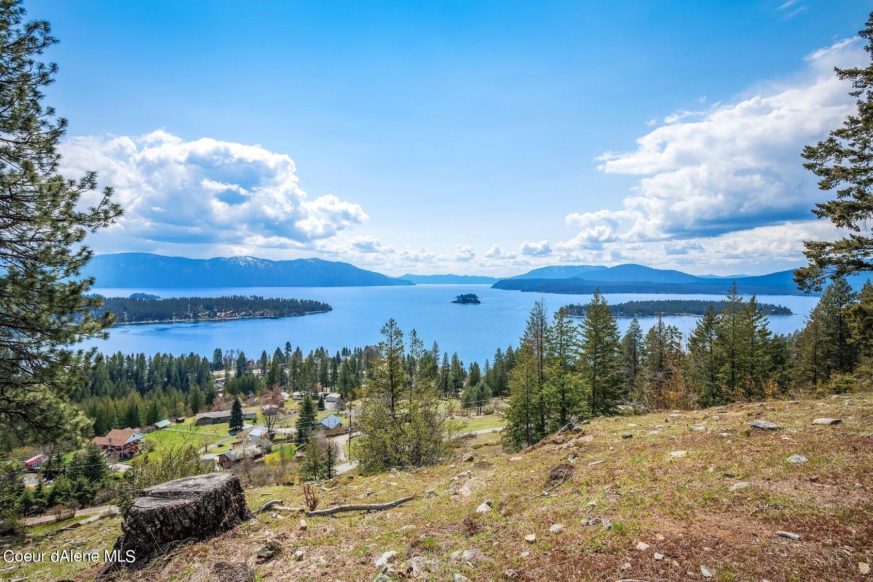 Vacant hillside lot overlooking a lake, forested islands, and distant mountains.