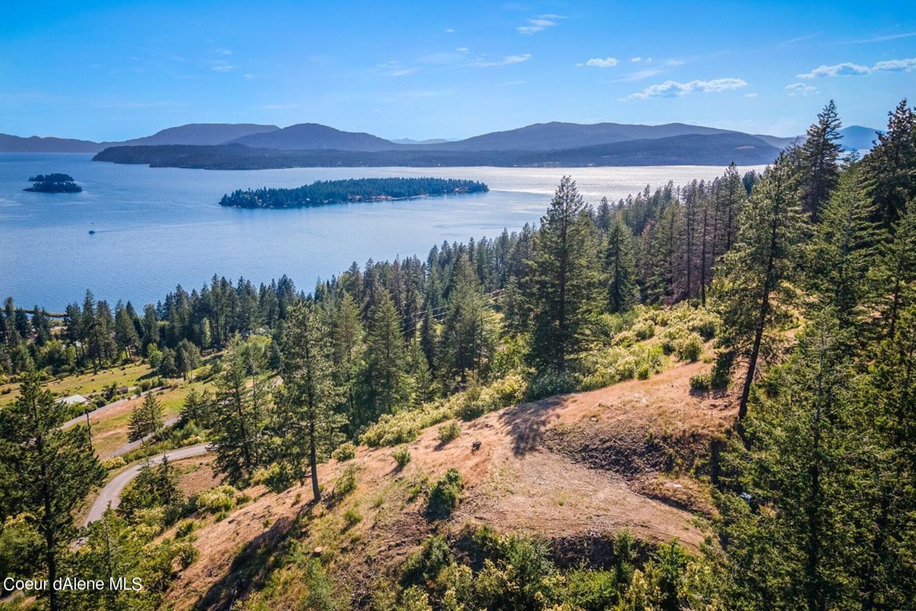 Wooded hillside property overlooking a lake, with islands and distant mountains.