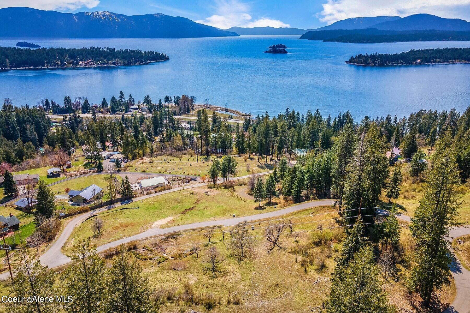 Aerial view of wooded lots beside a lake, with forested islands and mountain ranges beyond.