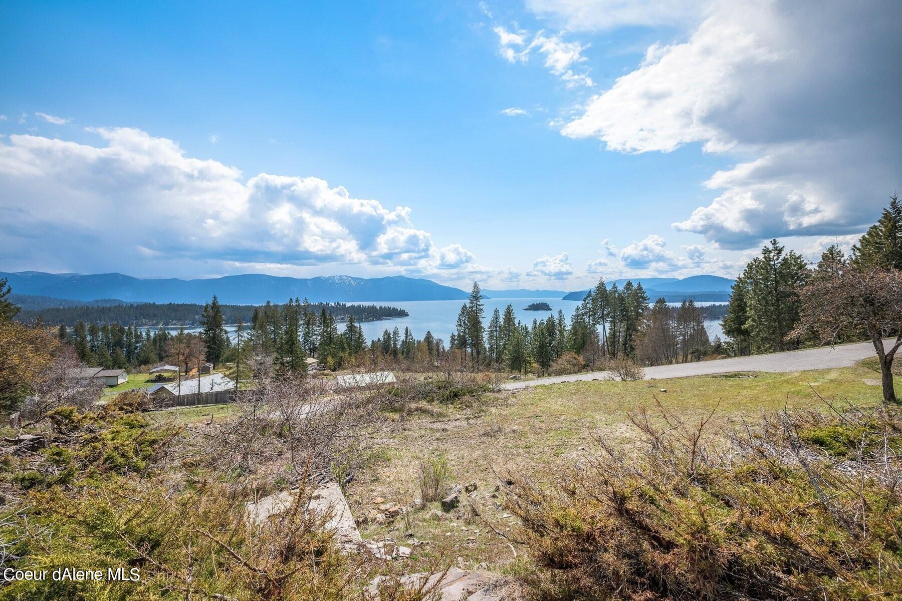 Vacant hillside lot overlooking a lake, forested shore, and distant mountains.