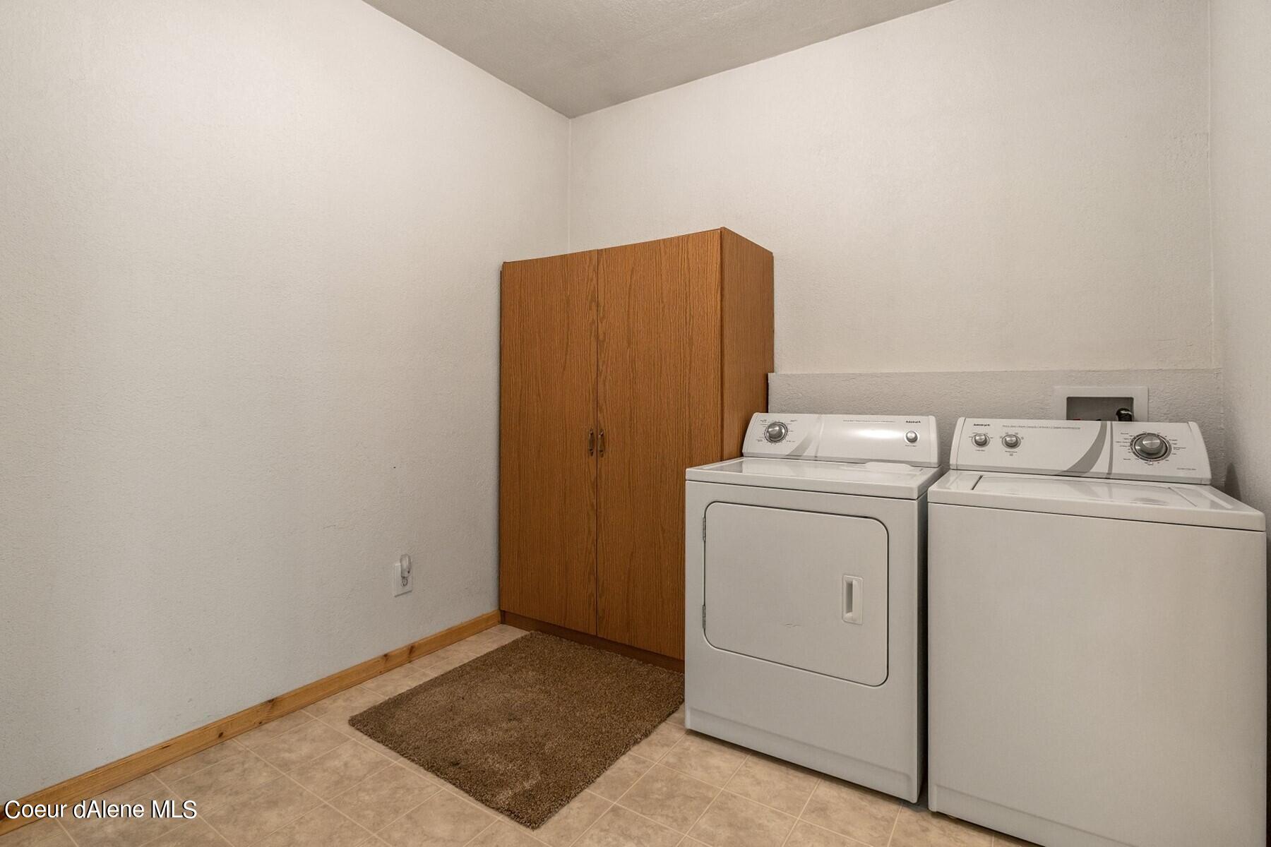 Laundry room with a washer, dryer, and tall wooden storage cabinet.