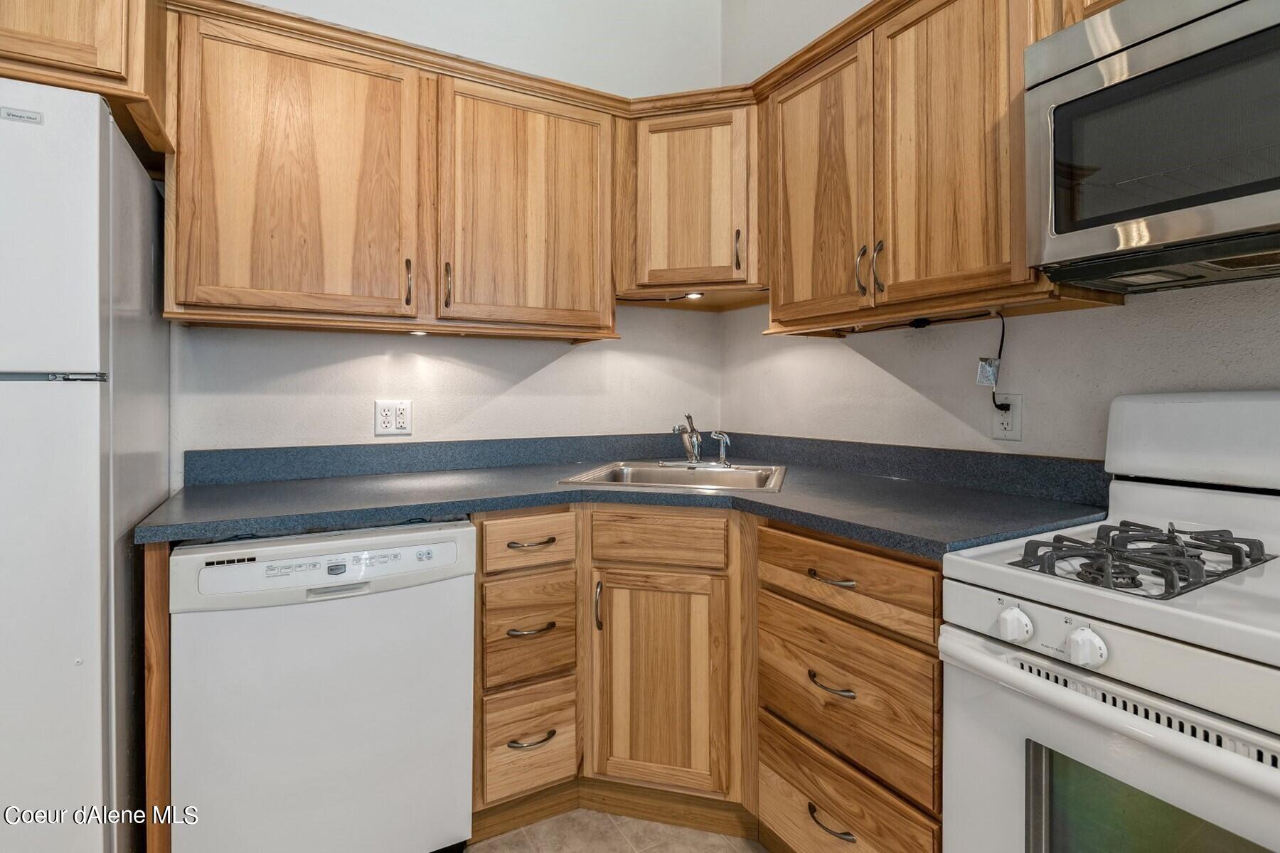 Kitchen with natural wood cabinets, blue-gray counters, and a white gas range.
