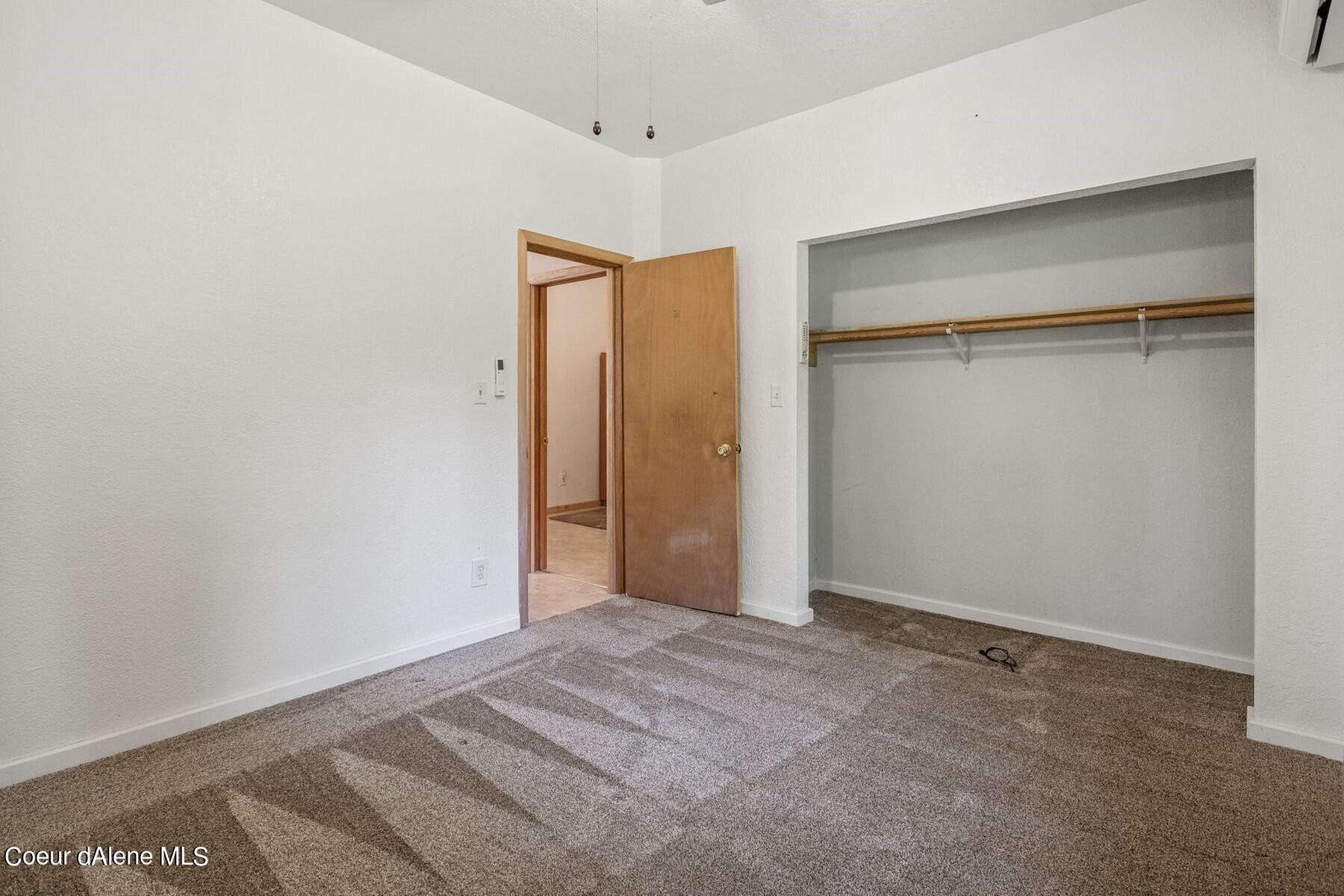 Vacant bedroom with beige carpet, an open built-in closet, and a wooden doorway.