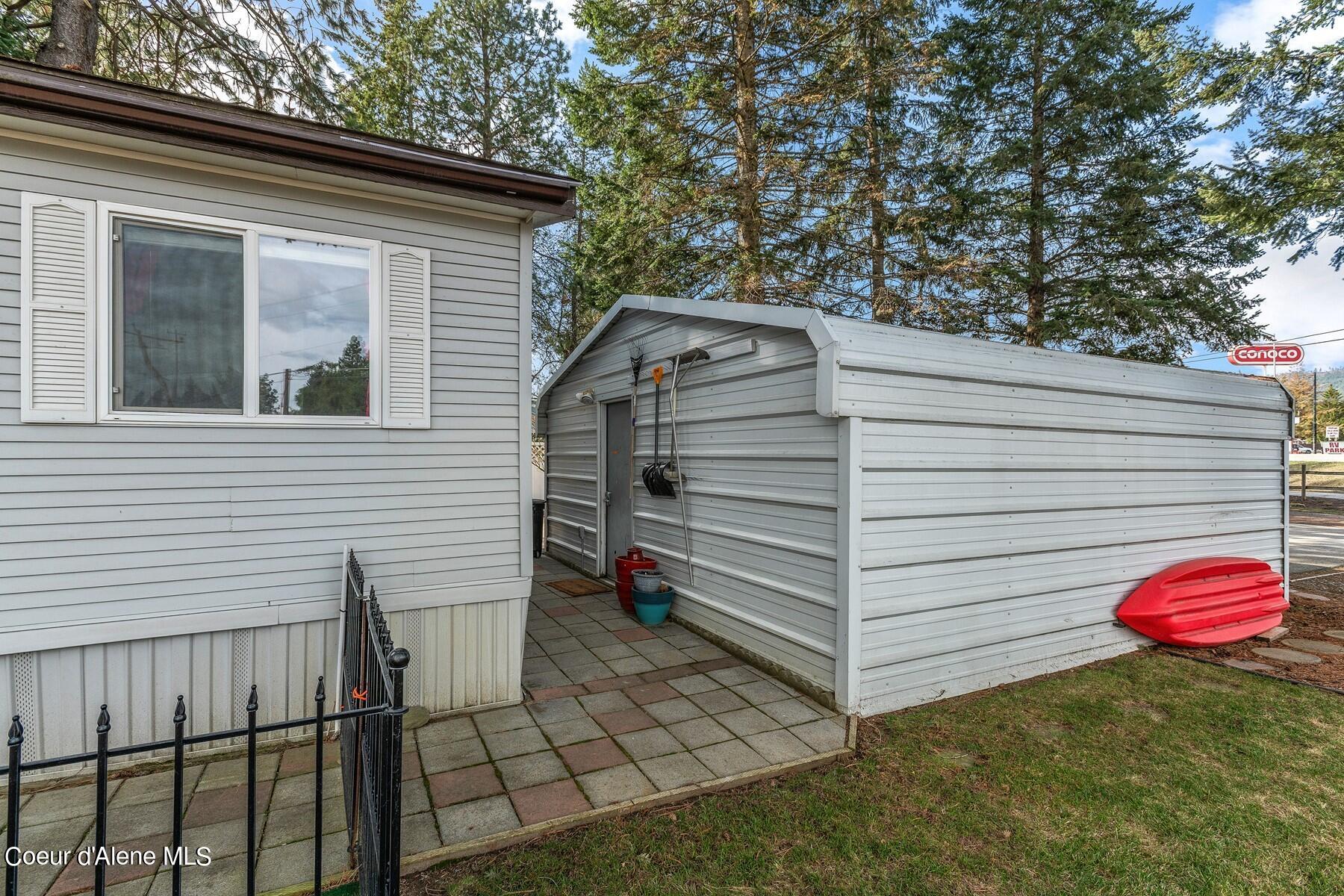 Home beside a large metal shed, with a paved walkway and red kayak.