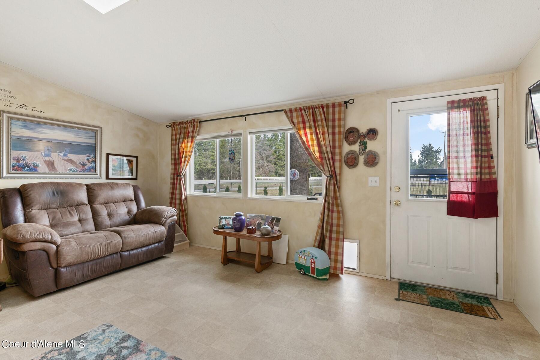 Living room with a brown leather sofa, plaid curtains, and a glass door to the balcony.