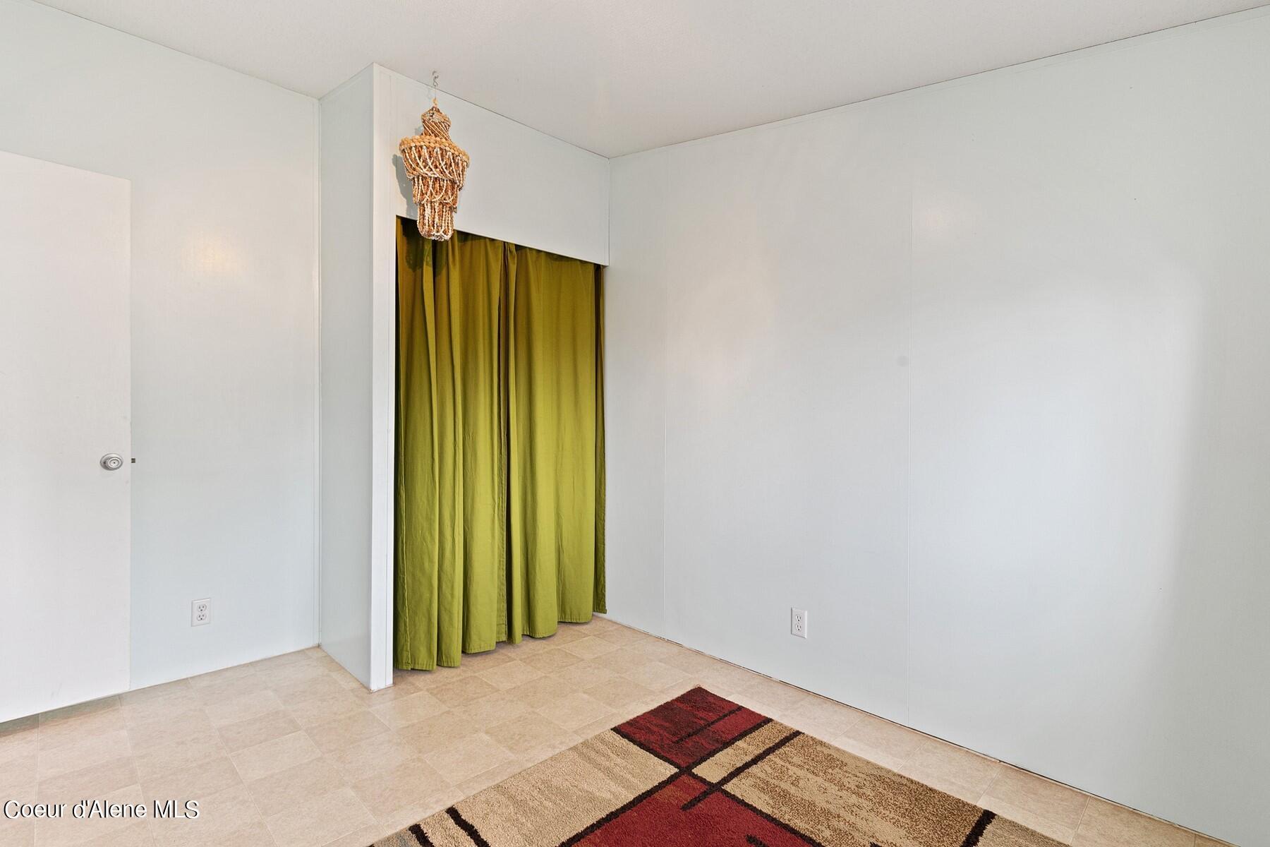 Interior room with green curtains, tiled floor, and a patterned rug.