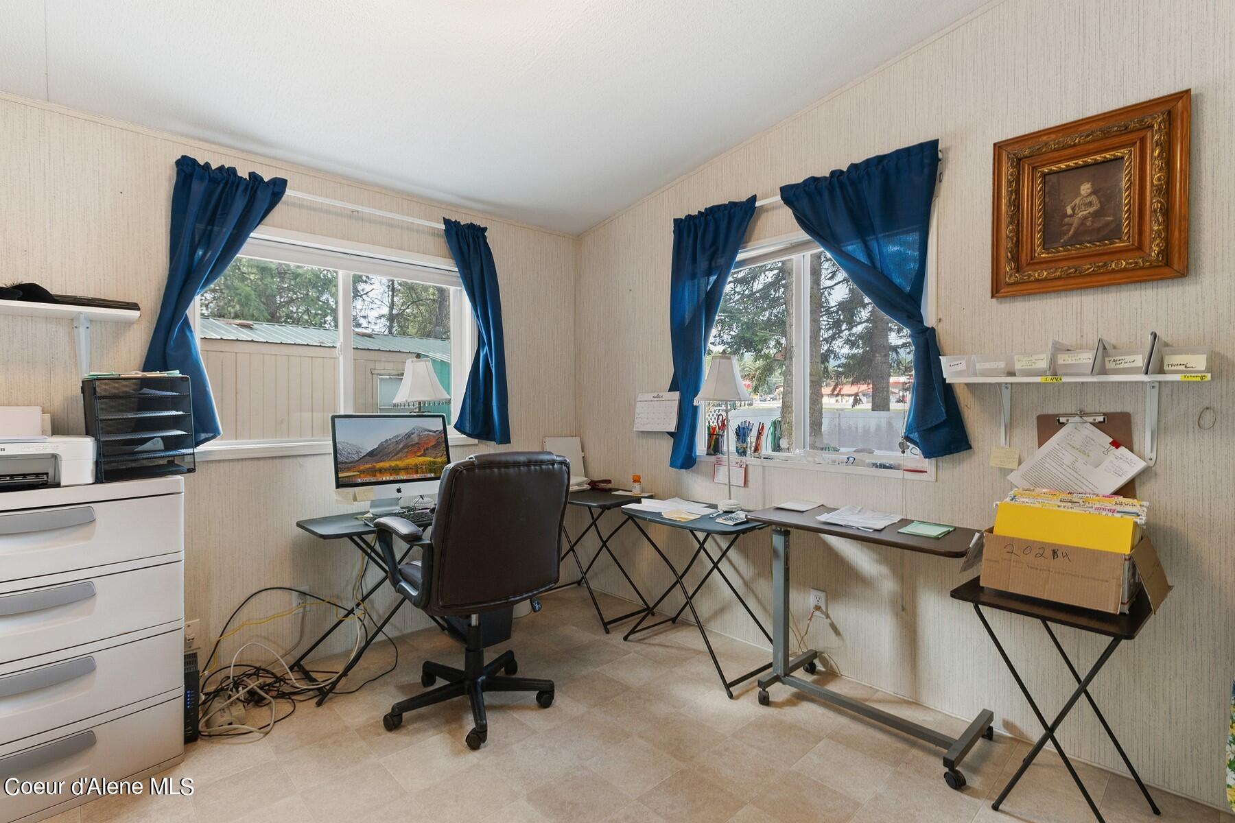 Office with blue-curtained windows, desks, a computer, and a printer.