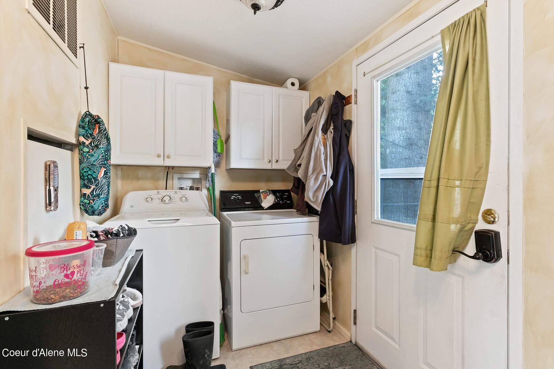 Laundry room with a washer, dryer, white cabinets, and a glass-panel door.