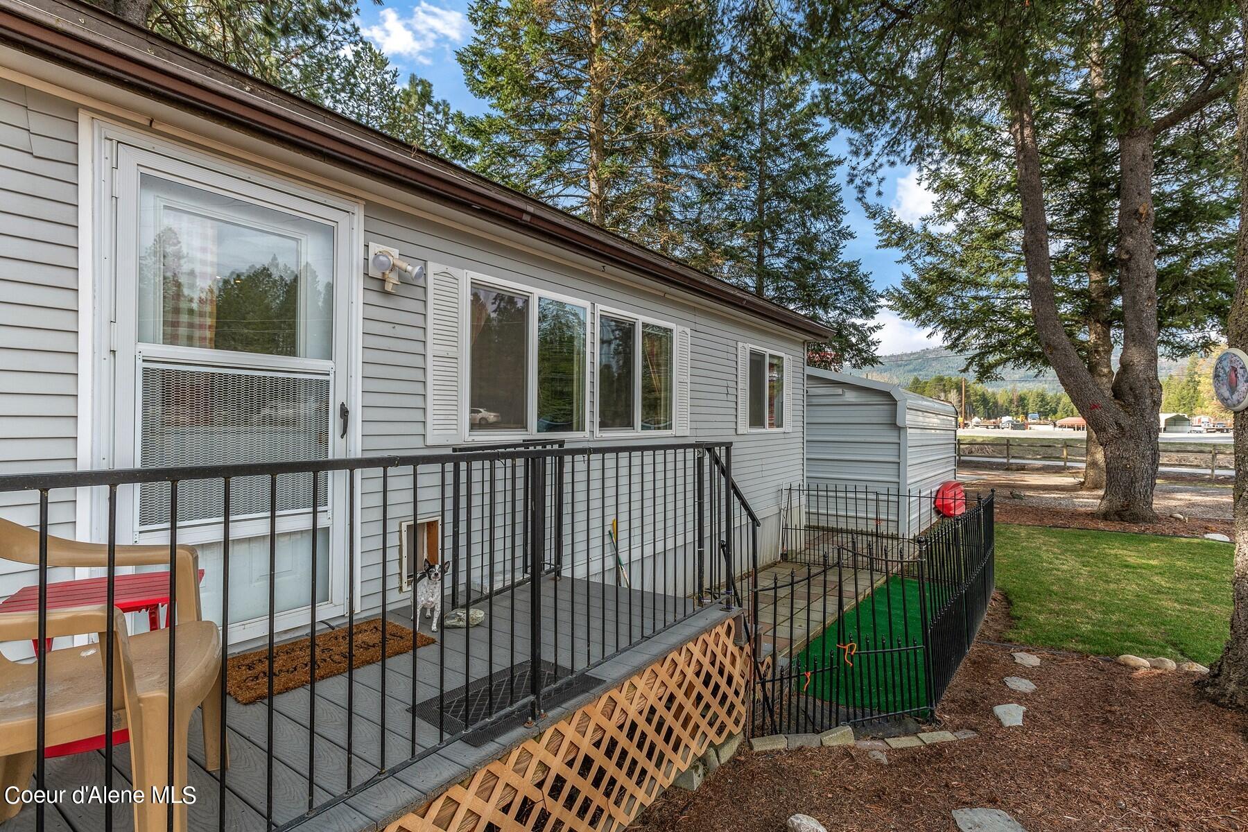 Home’s side deck with black railings and lattice skirting, outdoor chairs, and a small fenced yard.