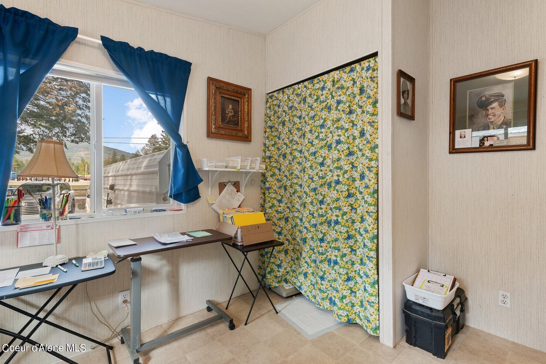 Compact office with blue curtains, worktables, and a colorful floral divider.