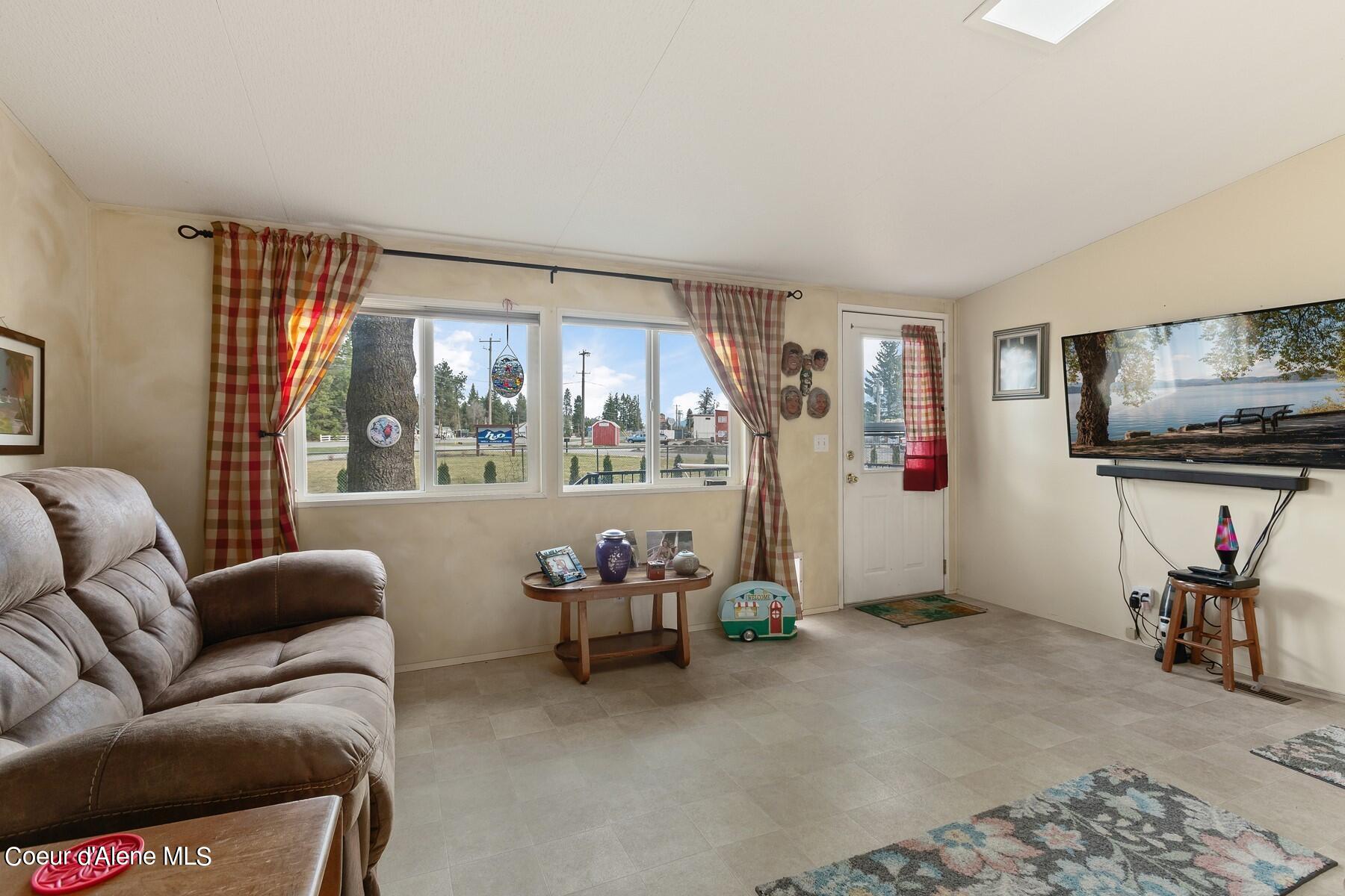 Living room with a brown sectional, plaid curtains, and wide windows.