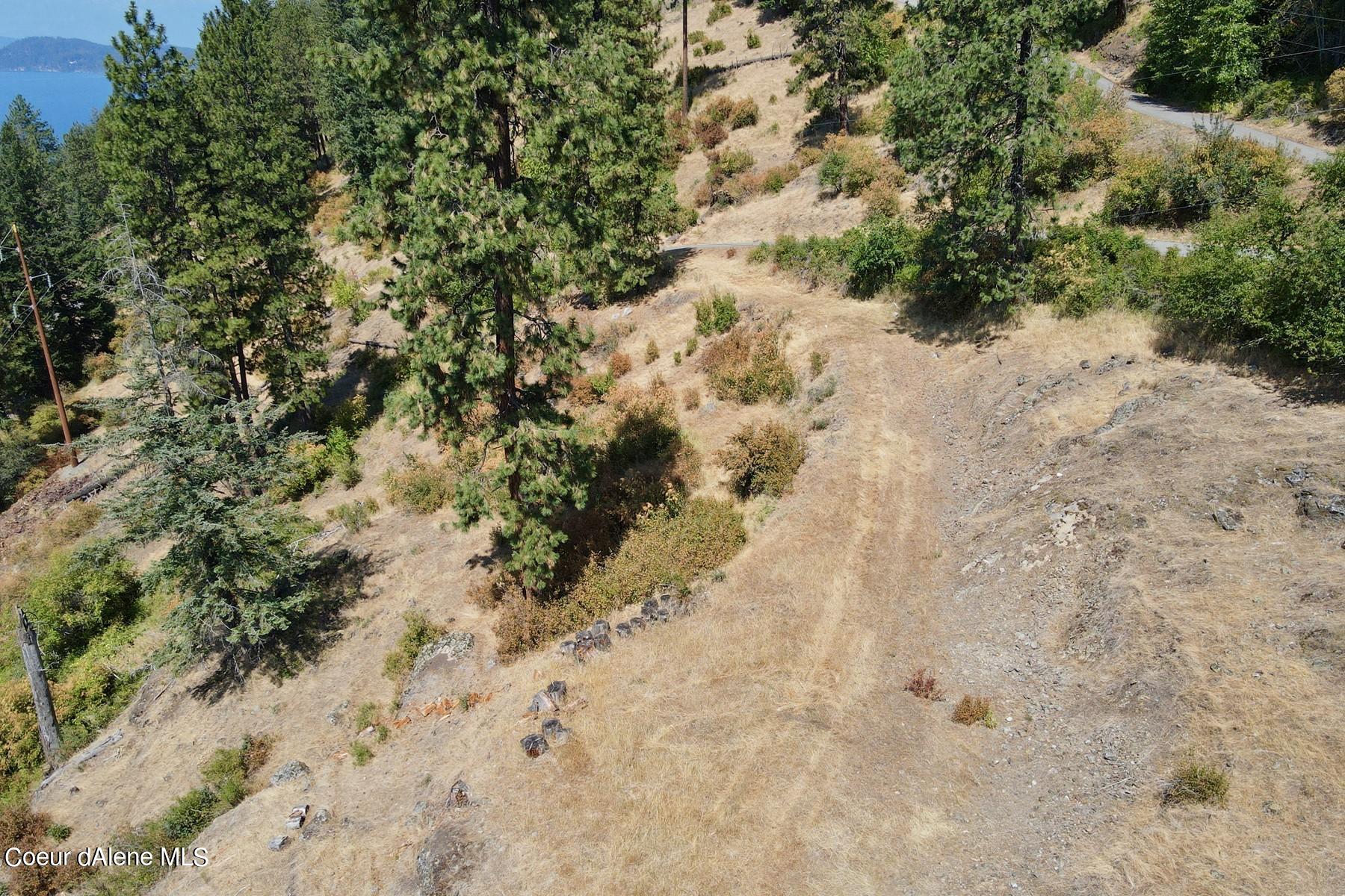 Sloping wooded parcel with rocky open ground and a distant lake view.