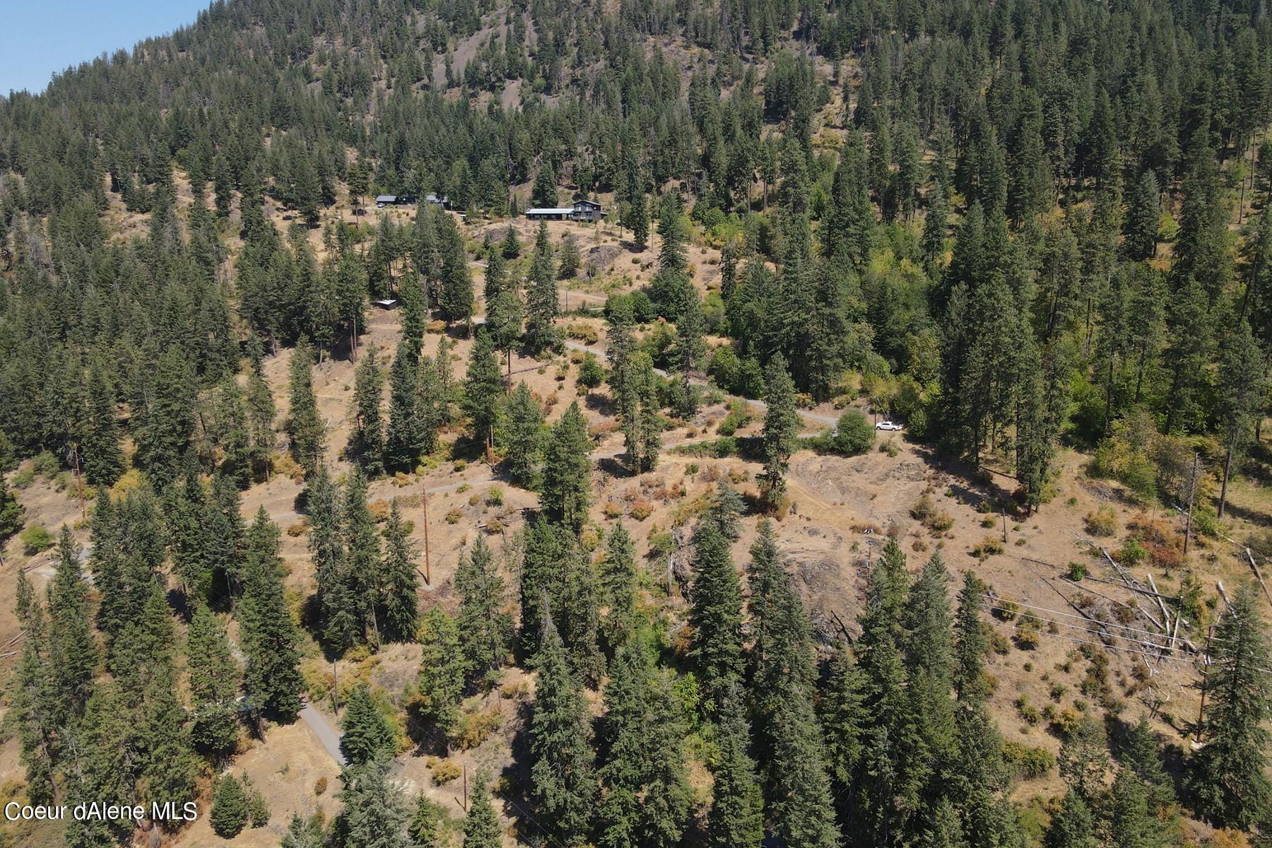 Aerial view of a wooded mountain property with scattered buildings and winding roads.