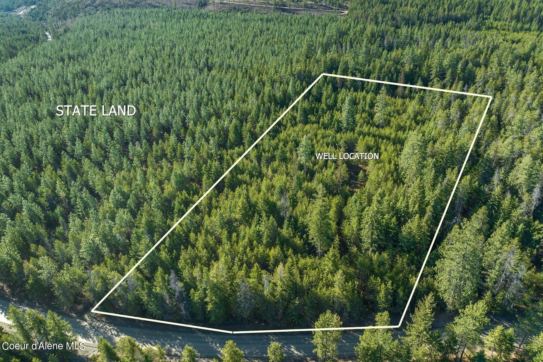 Aerial view of wooded parcel outlined beside a road; well location and state land marked.