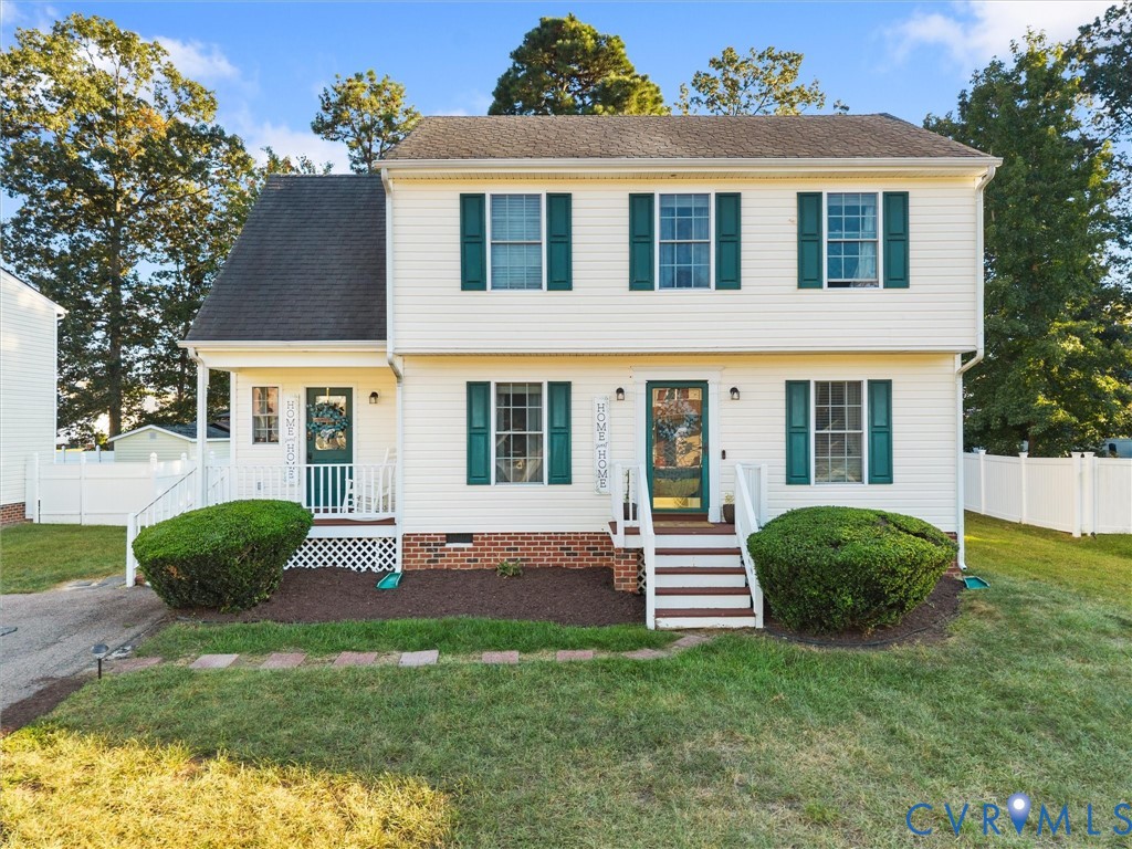 Two-story white house with teal shutters, front steps, trimmed shrubs, and a white fence.