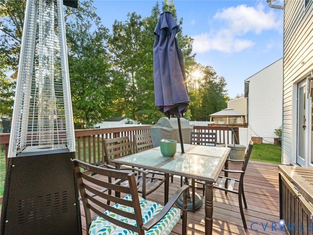 Furnished backyard deck with outdoor dining set, closed umbrella, and tall patio heater.