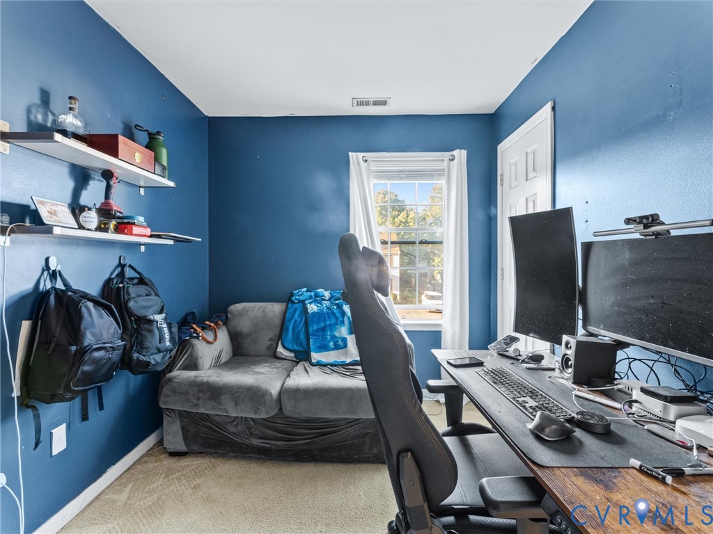 Blue home office with a dual-monitor desk, gray sofa, and bright window.