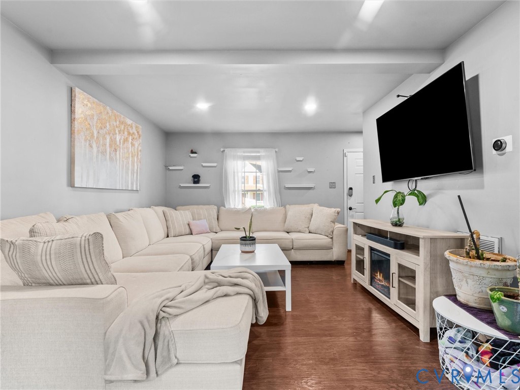 Living room with a cream sectional sofa, hardwood floors, and a wall-mounted television.