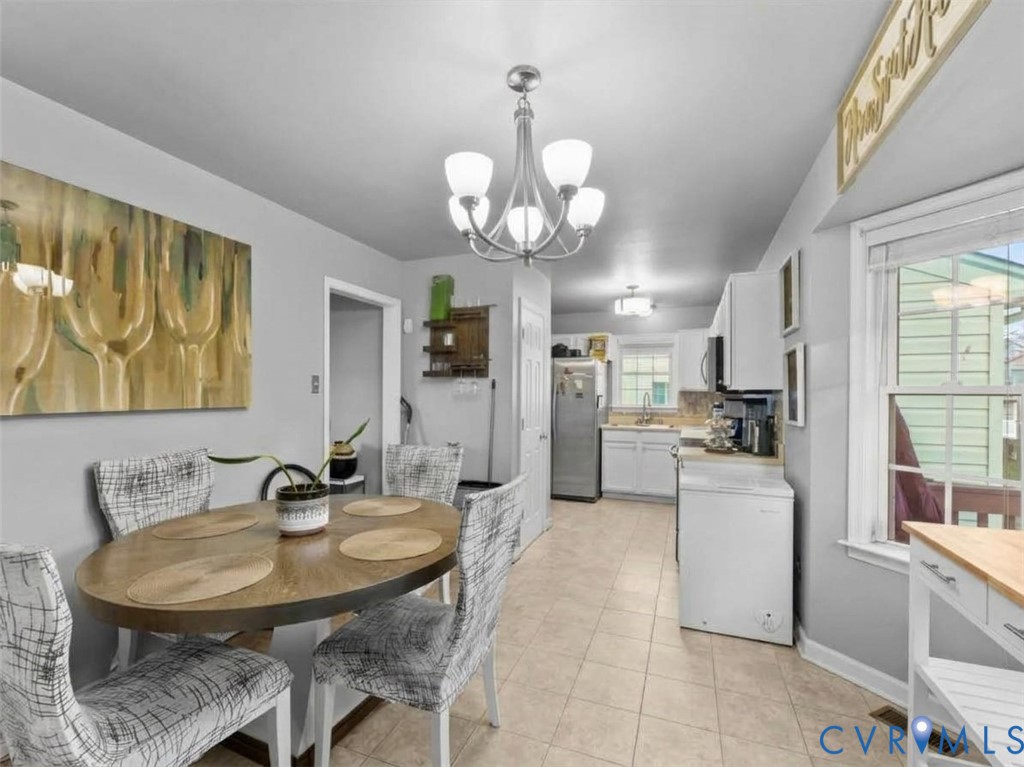 Dining area with a round wooden table and patterned chairs beside a compact kitchen.