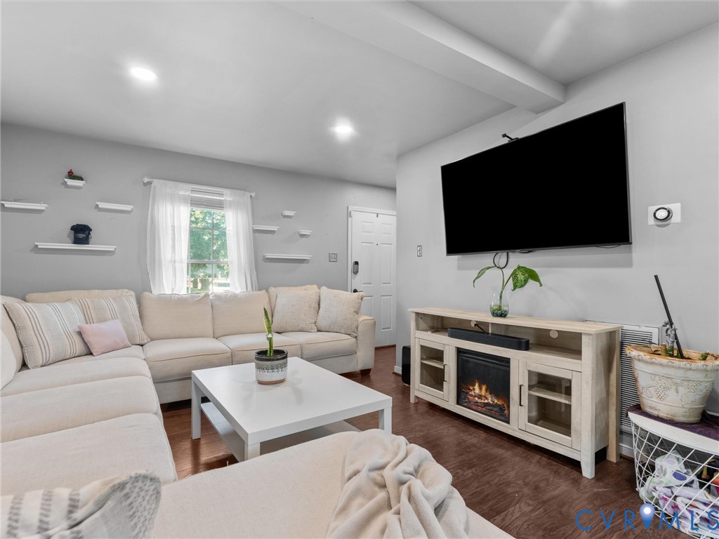 Living room with a cream sectional, wall-mounted TV, and media console with an electric fireplace.
