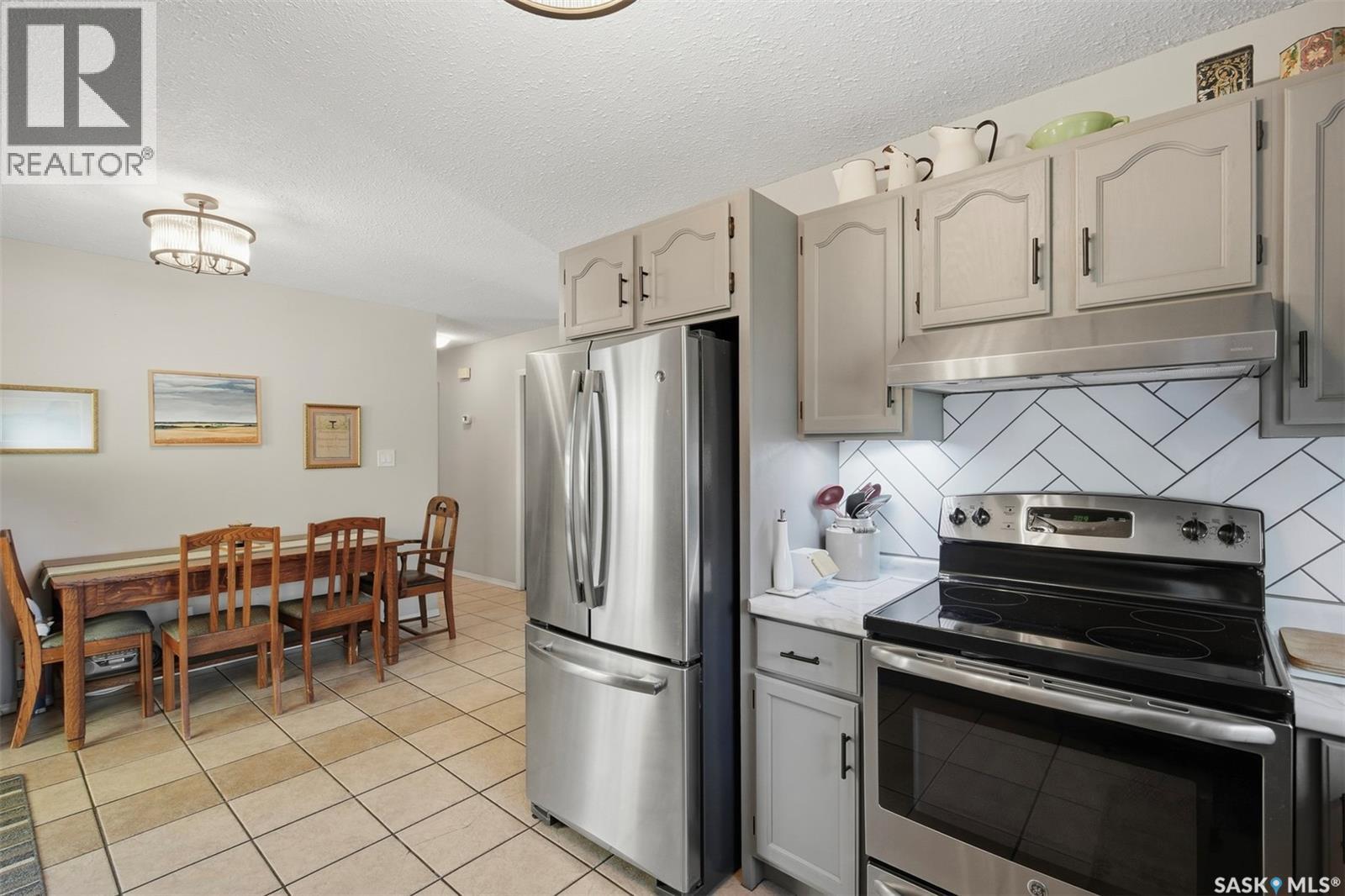 Kitchen with stainless steel appliances, white cabinets, and an adjoining dining area.