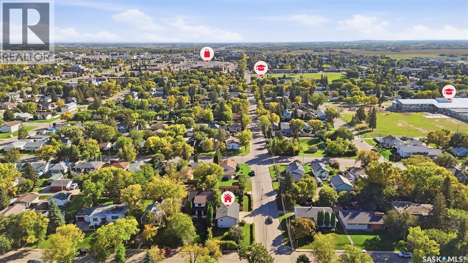 Aerial view of a tree-lined residential neighborhood with a main road and location markers.