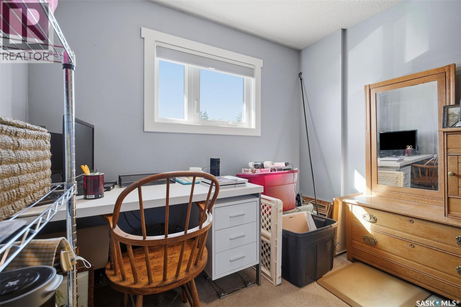 Small office with a white desk, wooden chair, and large wooden dresser.