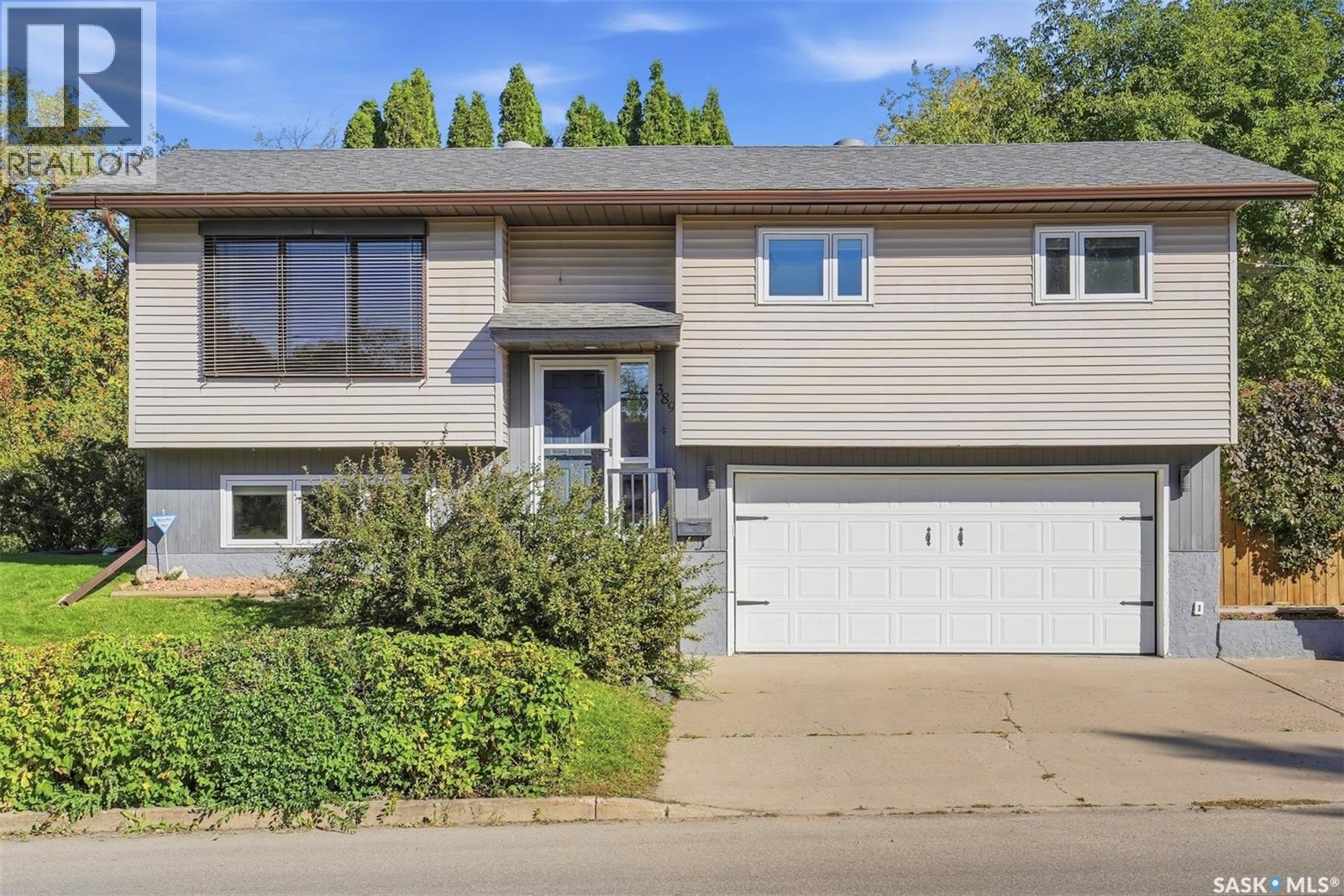 Split-level home with beige siding, a two-car garage, and a broad driveway.
