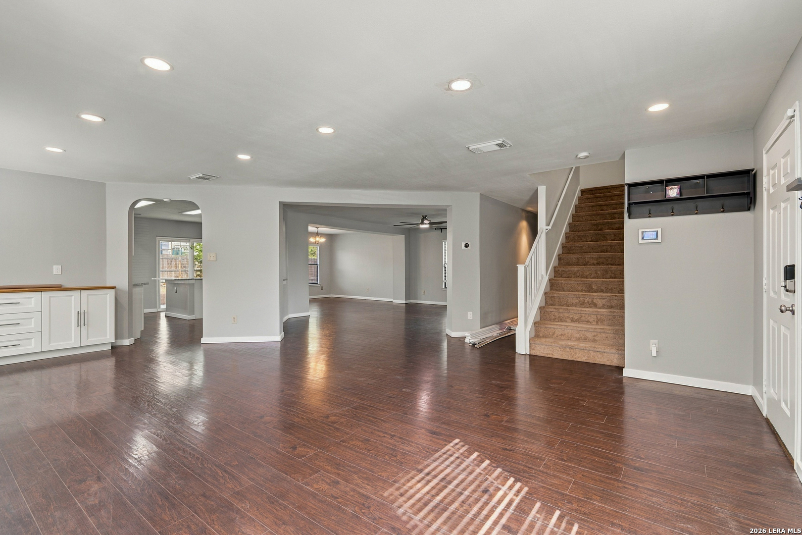 Open living area with dark wood-look floors, a carpeted staircase, and built-in cabinets.