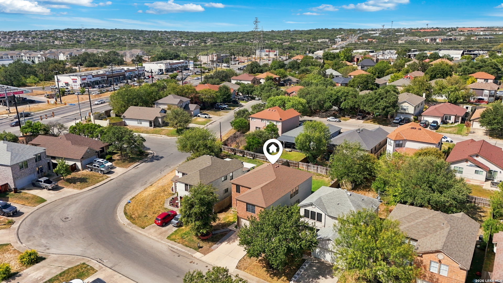 Aerial view of the marked home amid a residential neighborhood near a cul-de-sac and commercial area.