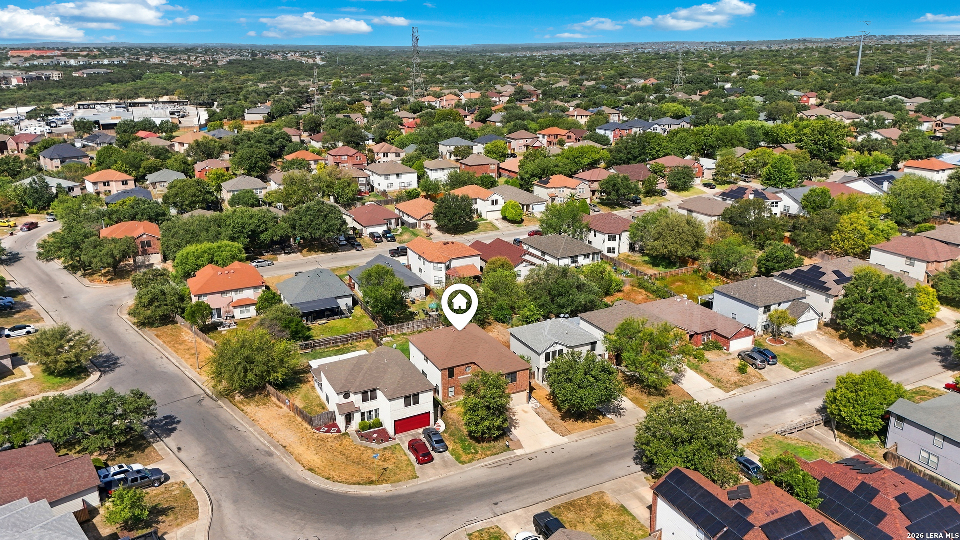 Aerial neighborhood view with a map pin marking the home among tree-lined streets.