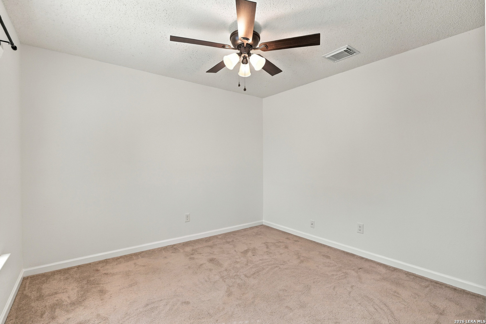 Empty bedroom with beige carpet and a dark wood ceiling fan with lights.