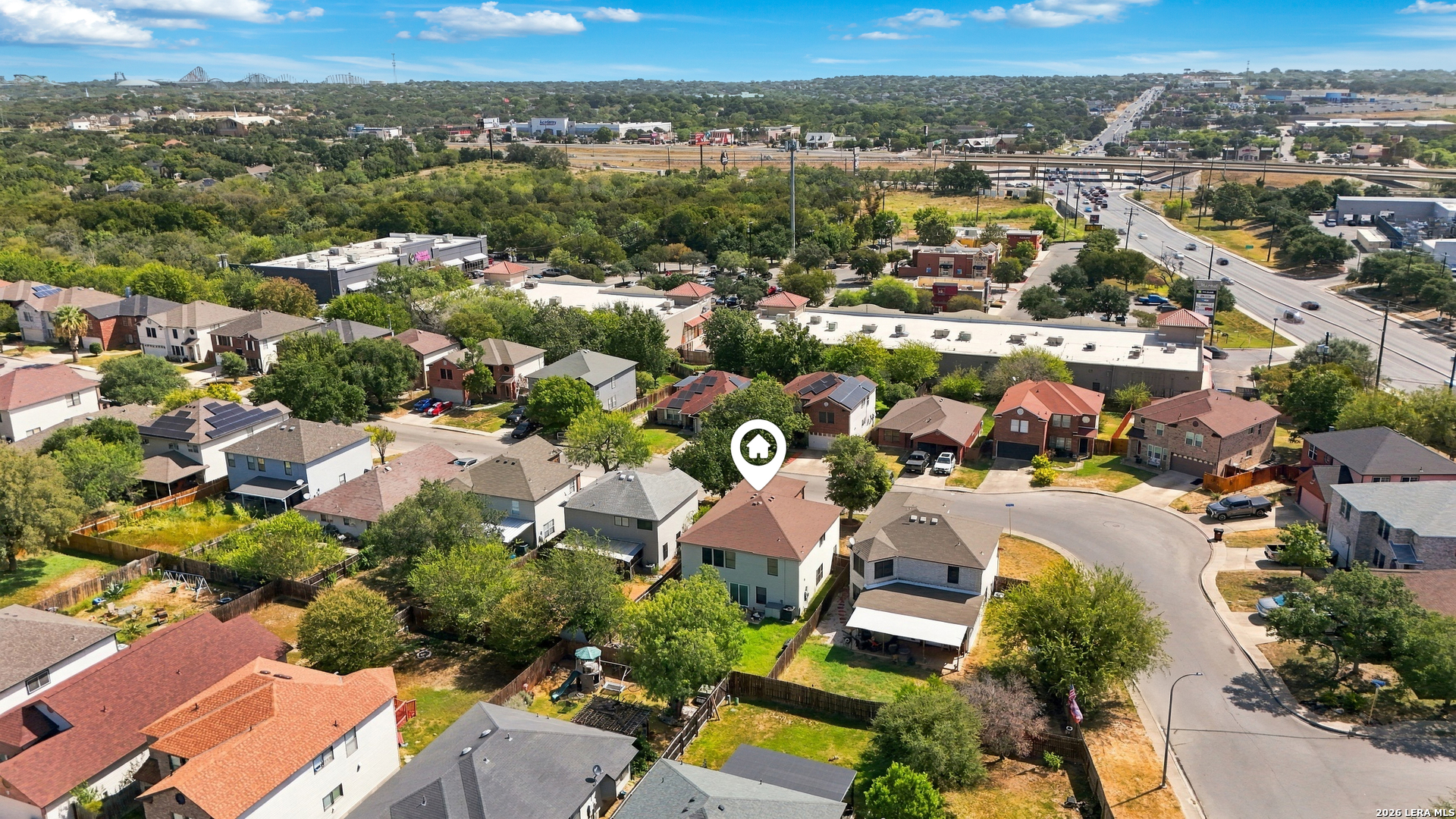Aerial view of the marked home among neighborhood houses, near a cul-de-sac and major roads.