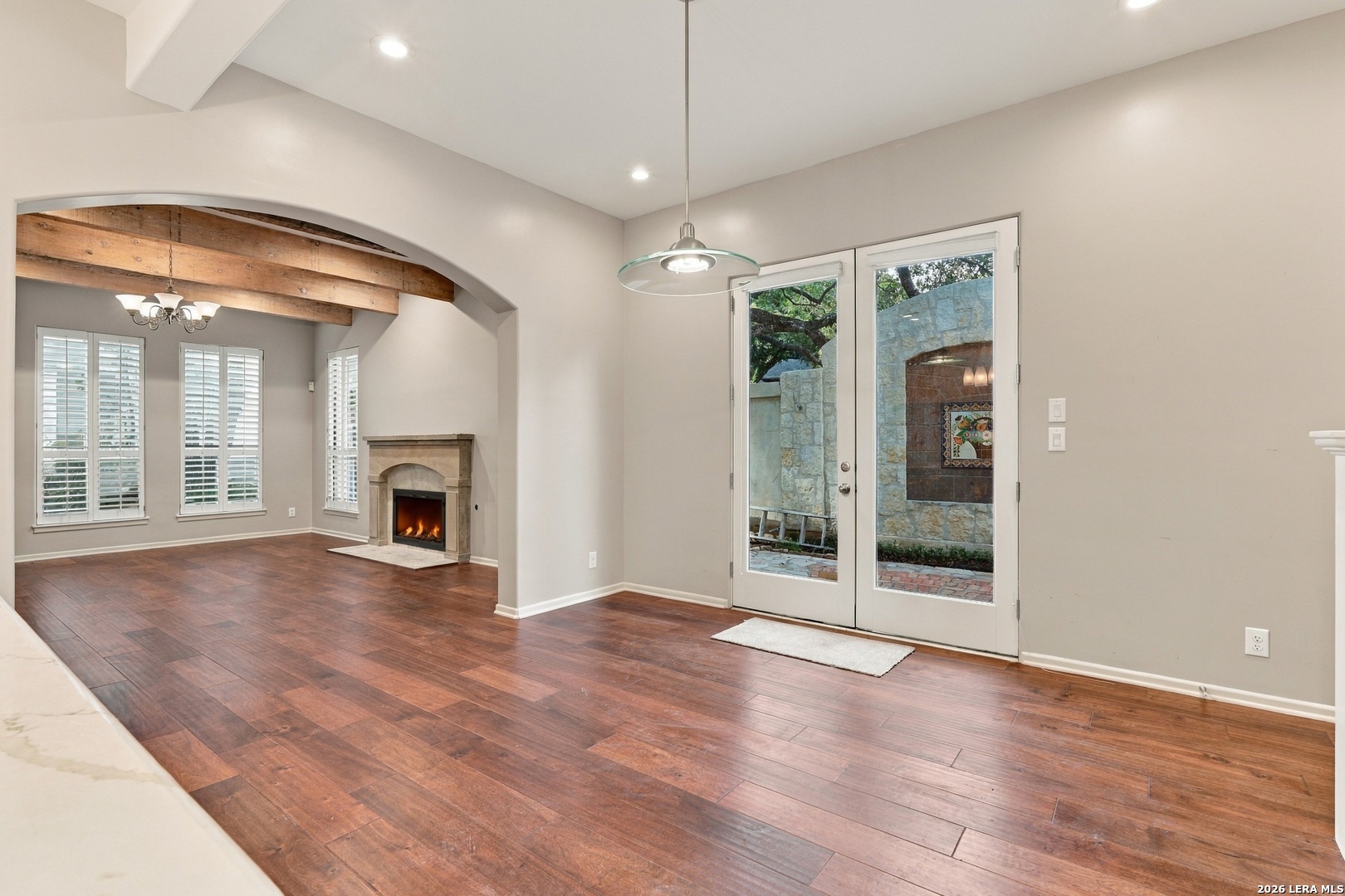 Living room with a stone fireplace, exposed wood beams, and glass patio doors.