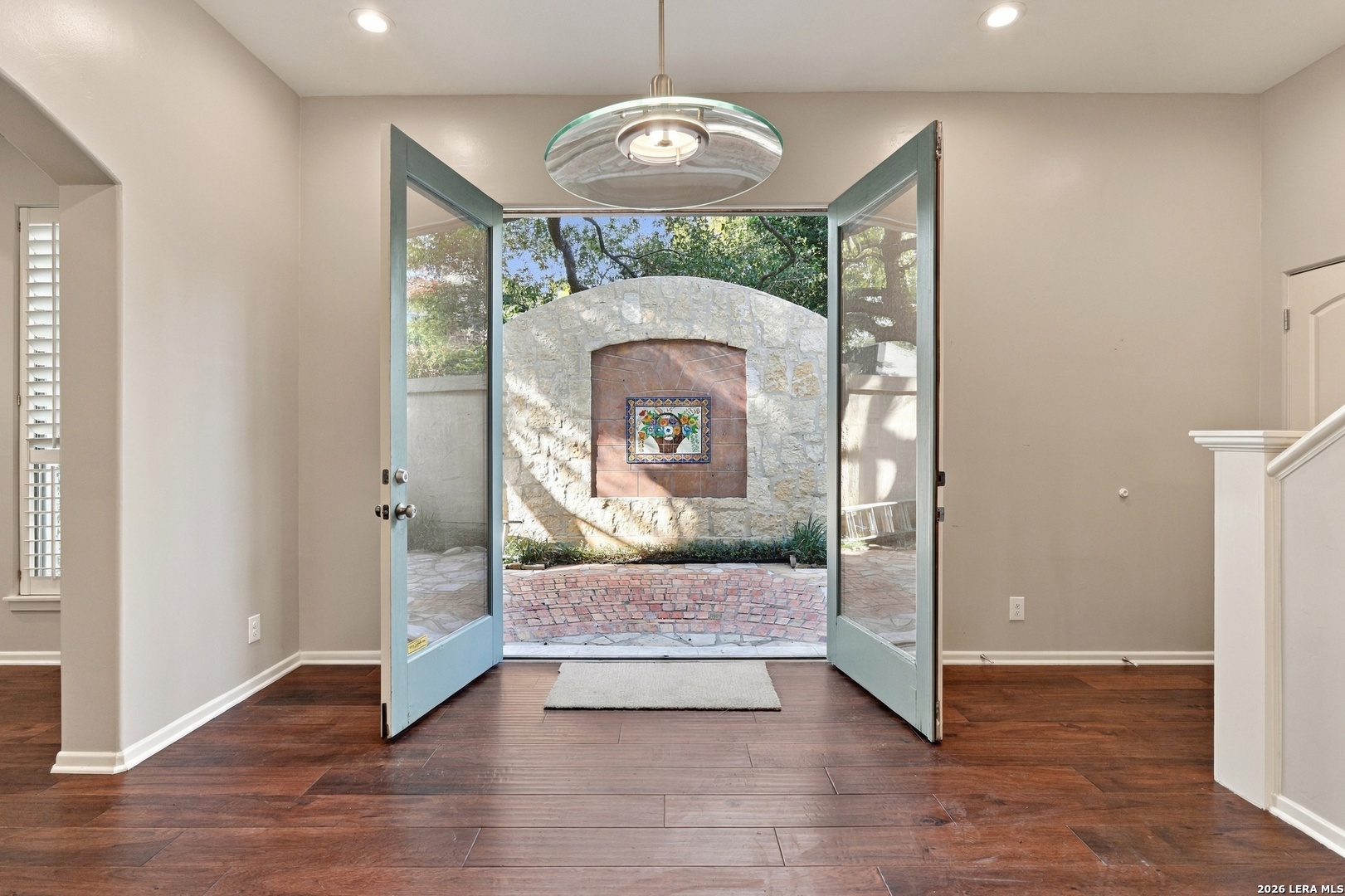 Entry room with open blue double doors framing a stone courtyard fireplace.