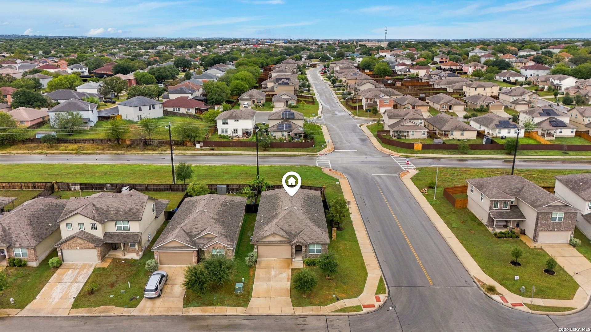 Aerial view of a marked home beside a neighborhood street intersection.