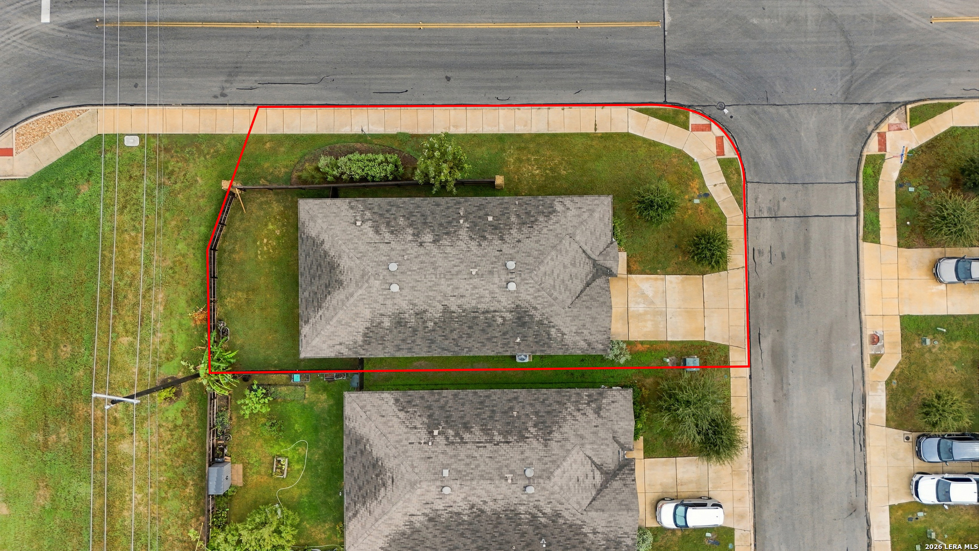 Aerial view of a corner-lot home and yard outlined in red to show the property boundary.