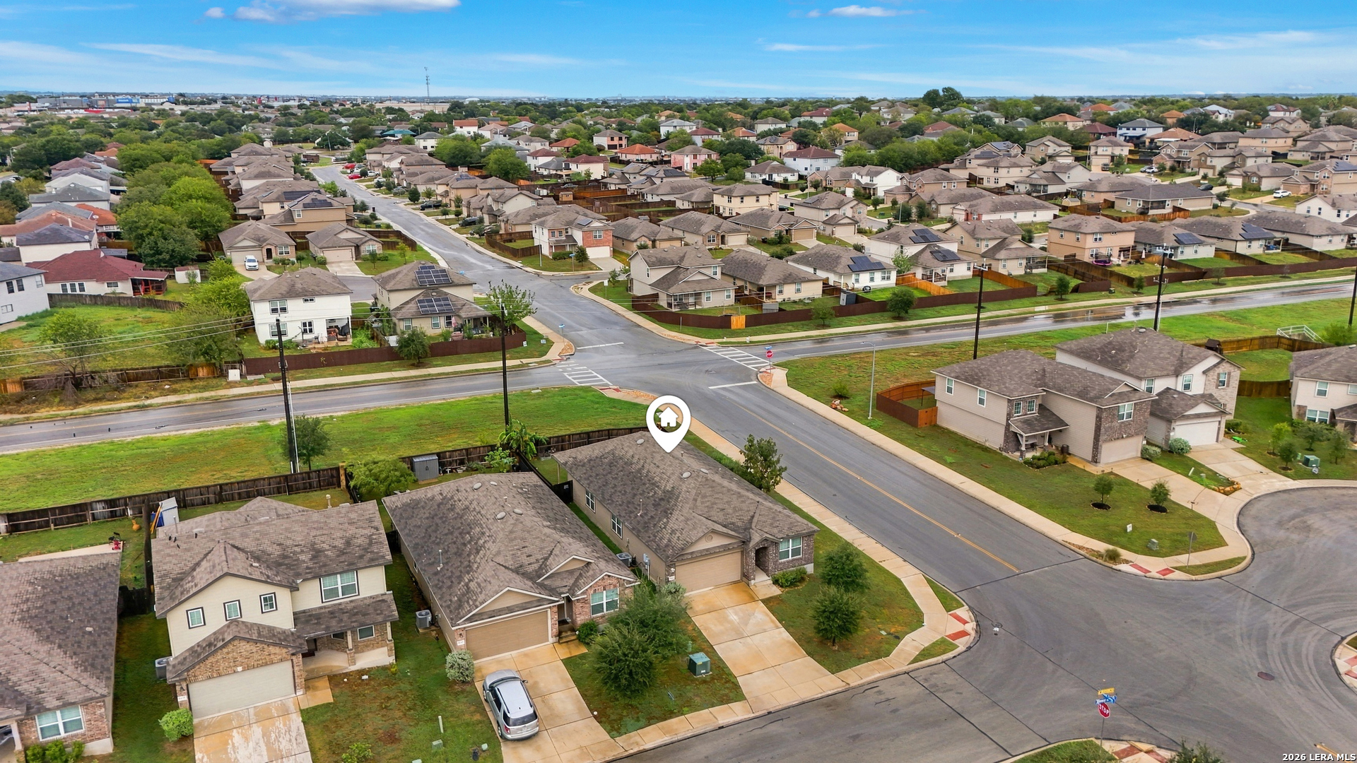 Aerial neighborhood view with a map pin marking a home near a street intersection.