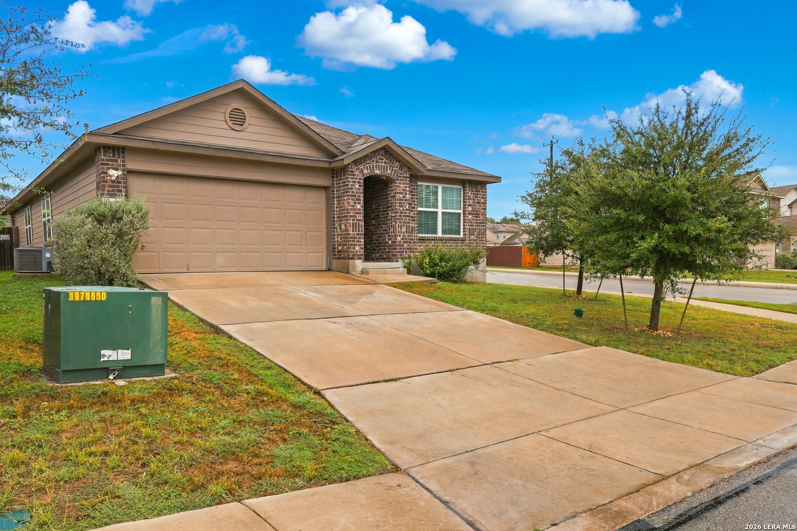 Single-story brick-and-siding home with an attached two-car garage and broad concrete driveway.